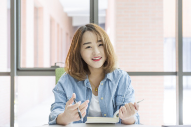 年轻美丽的女孩在桌子前看书