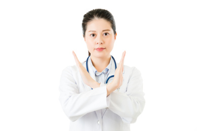 亚洲女子医生用听诊器秀拒绝停止姿势。隔绝在白色背景。医疗和健康理念