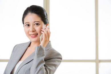 微笑的女人asain在办公室移动电话交谈