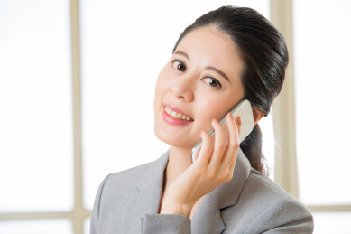 微笑的亚洲女子在办公室移动电话交谈