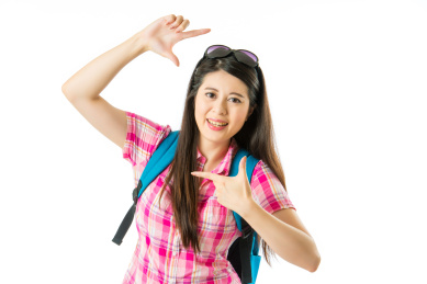 亚裔愉快的女游客在白色背景的手指框架