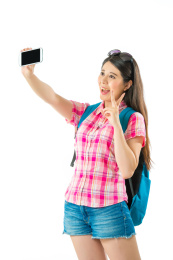 愉快亚洲女游客回吐自拍，胜利的手势在白色背景