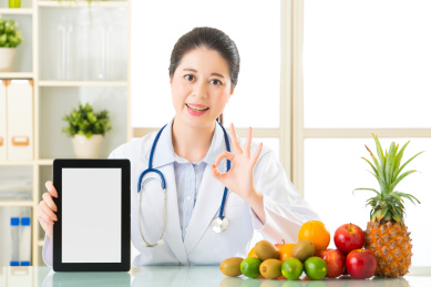 医生营养师水果持有数字平板电脑和好的符号，健康饮食