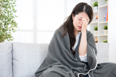 肖像病妇的感觉沙发上头痛。女人抓住感冒和流感。医疗和健康理念。混血亚洲的中国模式