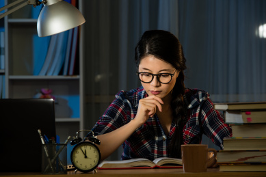年轻女子在晚上做作业。厌倦了西班牙裔女孩，大专以上学历。女学生为第二天的考试学习。混血亚洲的中国模式。