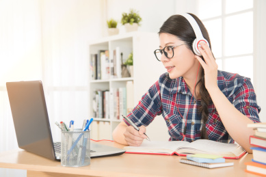 使用数字平板听耳机十几岁的女学生。混血亚洲的中国模式。