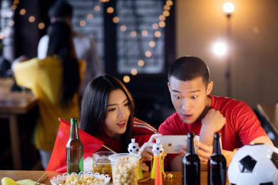 一对情侣在酒吧用手机紧张的观看足球比赛