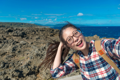 快乐的美少女背包客去海洋海岛旅游，享受当地的风景与舒适的风拍照自拍照。