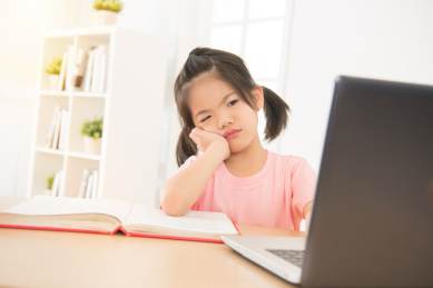 亚洲可爱的小女儿女孩的下巴在笔记本电脑前，在下午在房间里看着糊涂，伸手扶住。孩子学习的概念。