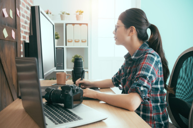 年轻漂亮的女工作照片企业职工的女孩在画与数字笔的设计和坐在办公桌编辑润饰摄影师的图片。