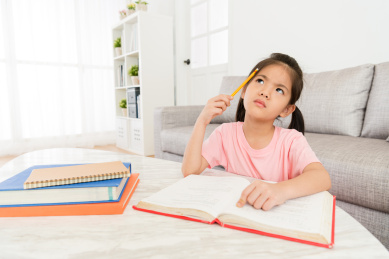 可爱甜美的小女孩在家里学习学校班级教科书并获得难点问题坐在客厅里想着如何解决。