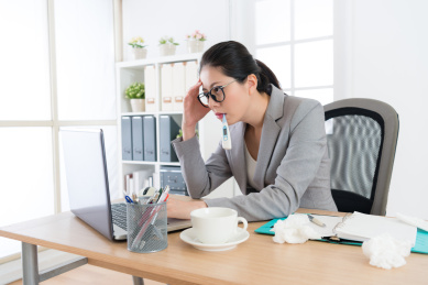 生病的公司职员的女子坚持在办公室工作。