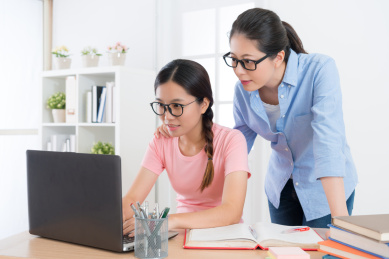微笑使用移动电脑在家里做与学习功课的老师漂亮的女人的学生，通过在线学习系统测试学习成果。
