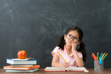 美丽可爱的女性儿童写有家庭作业的问题，思考解决的感觉难以黑板背景。