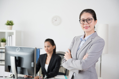2名成功的信心办公室女性像一个团队，交叉双臂一起工作面临的相机。