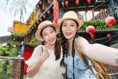 两个幸福的微笑迷人的女孩拍摄的自拍照片，照片上的著名景点九份台湾山阿妹茶馆背景。
