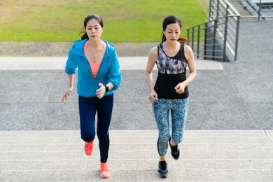 健康健身女子运动服慢跑和在城市球场户外跑步，在楼梯上工作了。