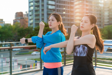 两个亚洲女运动员做运行锻炼后拉伸。积极的生活方式在城市。