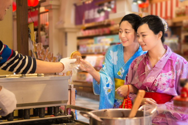 日本传统煎饼被服务的食品摊在浅草，日本开放式厨房。旅游节期间，活动期间甜点和穿着和服美女的亚洲女孩的手。