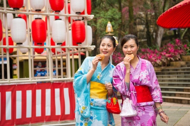 女游客去日本参加著名的节日庆祝穿着传统和服，吃着美味的铜锣烧的食物一起走在文化灯笼的街道。