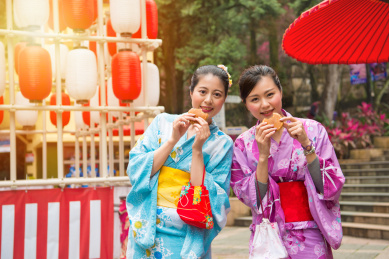年轻的女学生穿着和服的装束打扮，以庆祝街上行走，并在夏日午后的时间与阳光一起吃铜锣烧蛋糕。