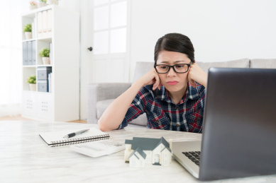 悲伤的年轻女子在感觉房子纳税时间不快和困惑。