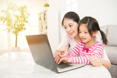 混血亚洲中国享受快乐的母亲和女儿在客厅里在家里玩电脑游戏的笔记本电脑。家庭活动的概念。