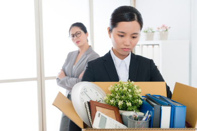 伤心漂亮的上班族女孩失去工作公司打包个人物品准备离开，她的经理看着她感到高兴。选择重点照片。