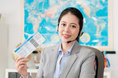 自信的年轻商人从事旅行社公司的在线服务中心，戴耳机显示相机机票脸。