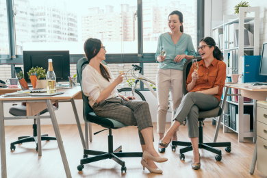 成功的团队庆祝概念。开朗的年轻人讨论与微笑的东西，而坐在或站在办公室的集团