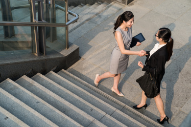 两个业务亚洲小姐相见，他们开始自己的面试之前。监事穿着礼服和员工在黑色suit.They将开始彼此良好的合作。他们和他们握手下楼。