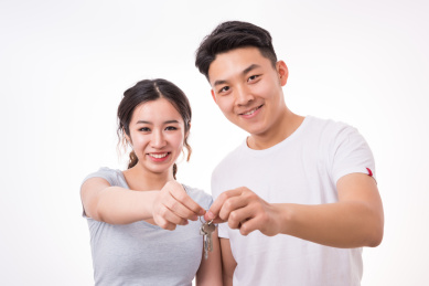 一对年轻的夫妻共同拿着一把钥匙，新房子，家