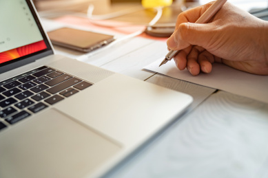 在电脑旁用钢笔做记、学习、工作场景