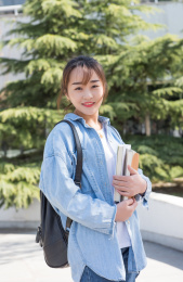 女大学生拿着书本在户外