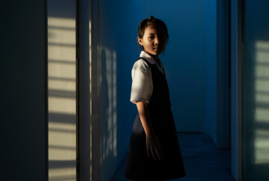 Little Asian girl stand alone in house . Sunset light shining pass through the window.