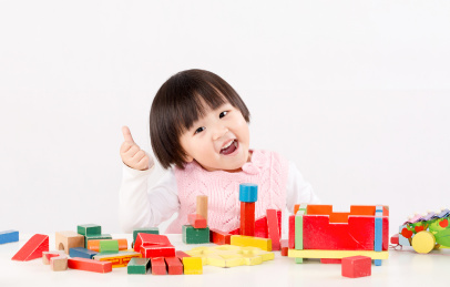 伸着大拇指的小女孩开心玩积木