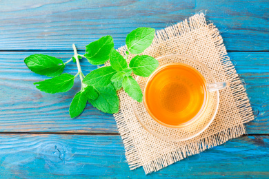 新鲜的薄荷叶和一杯茶在蓝色的桌子上