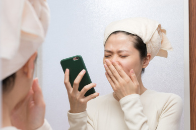 女生刚起床在浴室打哈看手机