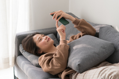 女生睡在沙发上玩手机
