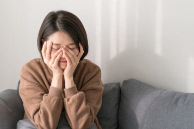 女生手捂脸坐沙发上