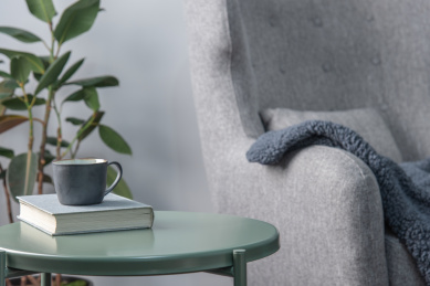 明亮的起居室内一本书和一个咖啡杯放在绿色金属边桌上