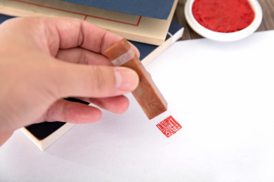 手拿石质印章盖在白纸上