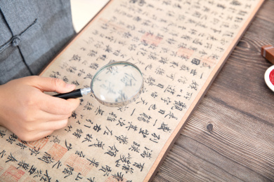 书法艺术家手持放大镜仔细欣赏王羲之的兰亭集序作品