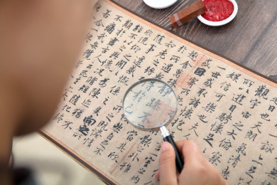书法艺术家手持放大镜仔细欣赏王羲之的兰亭集序作品