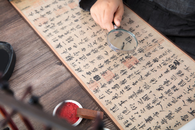 书法艺术家手持放大镜仔细欣赏王羲之的兰亭集序作品