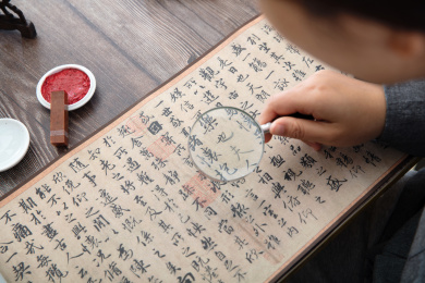书法艺术家手持放大镜仔细欣赏王羲之的兰亭集序作品