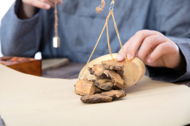 中医大夫把秤盘里的中药大黄倒在草纸上