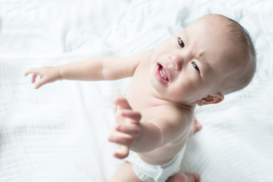 只穿着纸尿裤的幼儿在床上哭闹