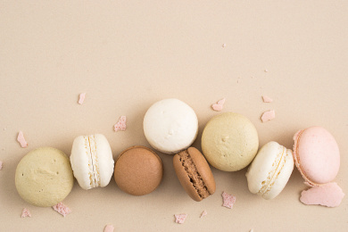 各种颜色的马卡龙摆放在咖啡色背景上面