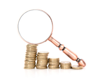 白背景上一排欧元硬币和观察工具放大镜